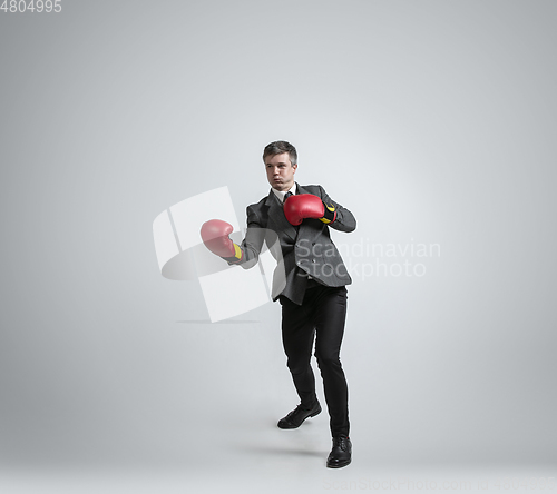 Image of Caucasian man in office clothes boxing isolated on grey studio background