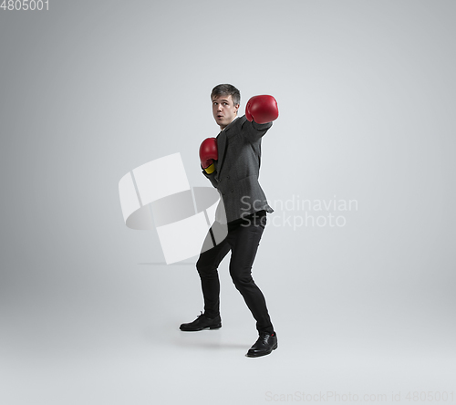 Image of Caucasian man in office clothes boxing isolated on grey studio background