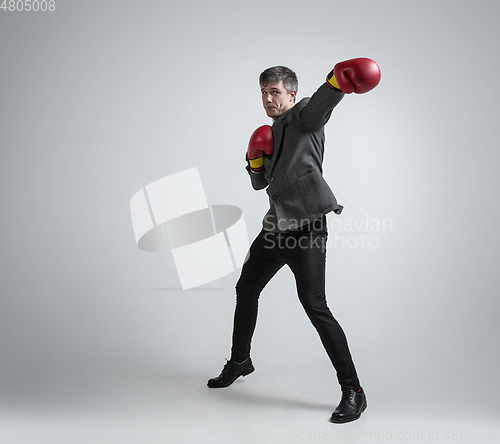 Image of Caucasian man in office clothes boxing isolated on grey studio background