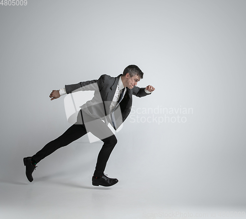 Image of Caucasian man in office clothes running isolated on grey studio background
