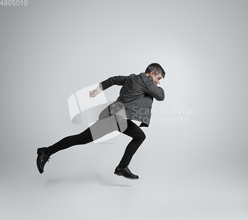 Image of Caucasian man in office clothes running isolated on grey studio background