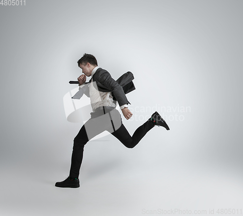 Image of Caucasian man in office clothes running isolated on grey studio background