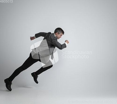 Image of Caucasian man in office clothes running isolated on grey studio background