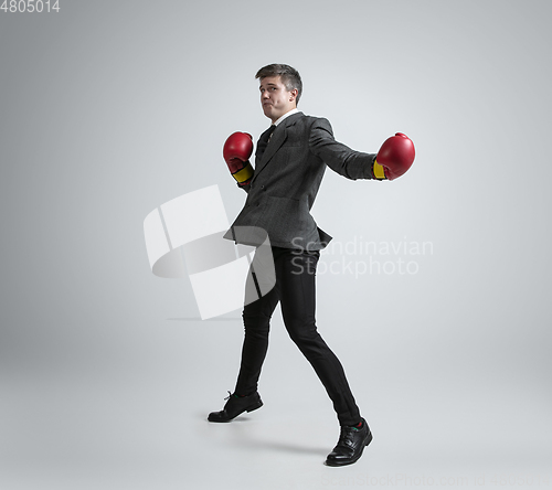 Image of Caucasian man in office clothes boxing isolated on grey studio background