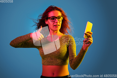 Image of Caucasian woman\'s portrait isolated on blue studio background in neon light