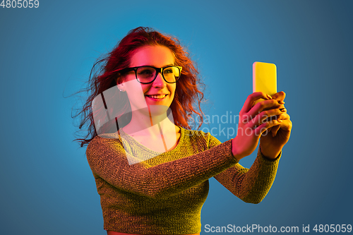 Image of Caucasian woman\'s portrait isolated on blue studio background in neon light