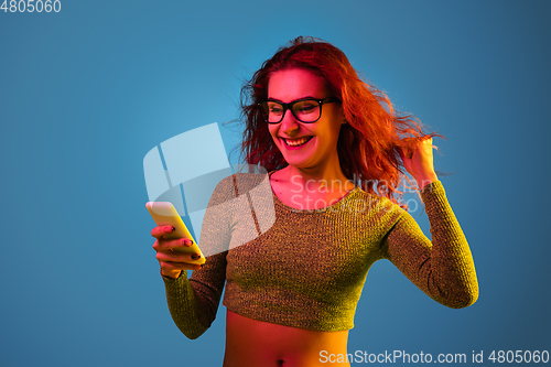 Image of Caucasian woman\'s portrait isolated on blue studio background in neon light