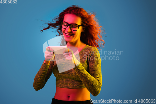 Image of Caucasian woman\'s portrait isolated on blue studio background in neon light