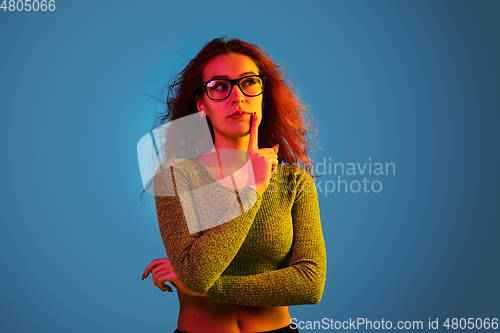 Image of Caucasian woman\'s portrait isolated on blue studio background in neon light