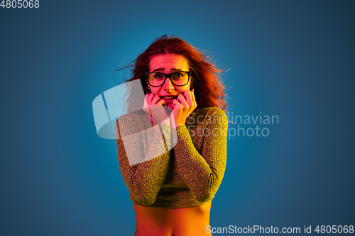 Image of Caucasian woman\'s portrait isolated on blue studio background in neon light