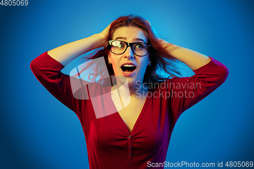 Image of Caucasian woman\'s portrait isolated on blue studio background in neon light