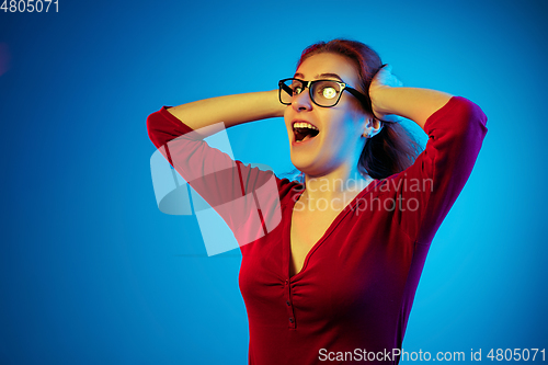 Image of Caucasian woman\'s portrait isolated on blue studio background in neon light