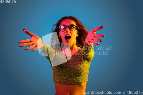 Image of Caucasian woman\'s portrait isolated on blue studio background in neon light