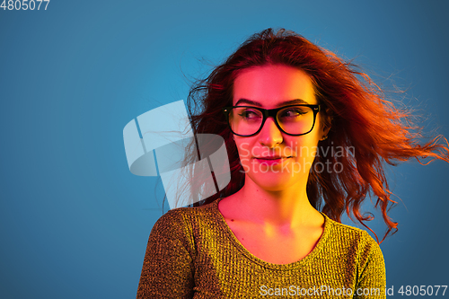 Image of Caucasian woman\'s portrait isolated on blue studio background in neon light