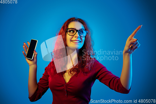 Image of Caucasian woman\'s portrait isolated on blue studio background in neon light