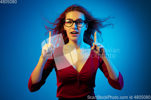 Image of Caucasian woman\'s portrait isolated on blue studio background in neon light