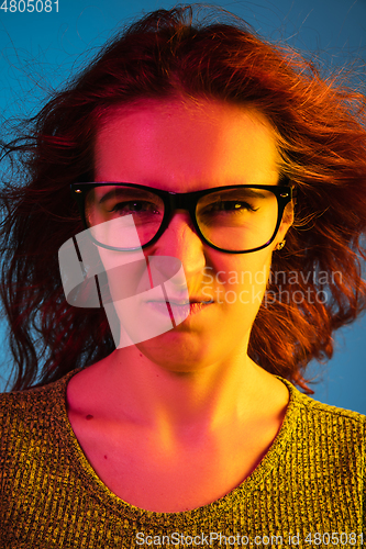 Image of Caucasian woman\'s portrait isolated on blue studio background in neon light