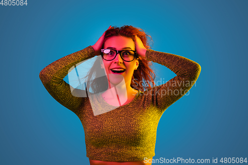 Image of Caucasian woman\'s portrait isolated on blue studio background in neon light
