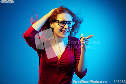Image of Caucasian woman\'s portrait isolated on blue studio background in neon light