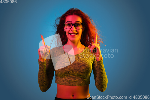 Image of Caucasian woman\'s portrait isolated on blue studio background in neon light