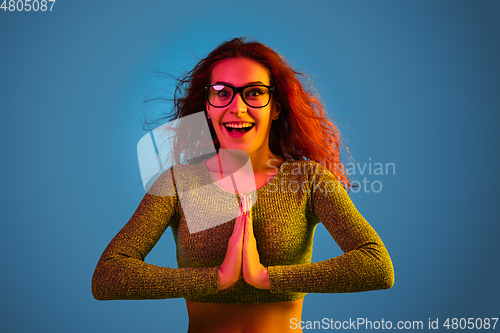 Image of Caucasian woman\'s portrait isolated on blue studio background in neon light