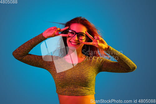 Image of Caucasian woman\'s portrait isolated on blue studio background in neon light