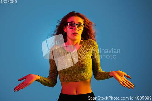 Image of Caucasian woman\'s portrait isolated on blue studio background in neon light