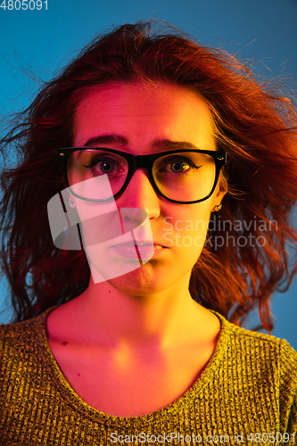 Image of Caucasian woman\'s portrait isolated on blue studio background in neon light