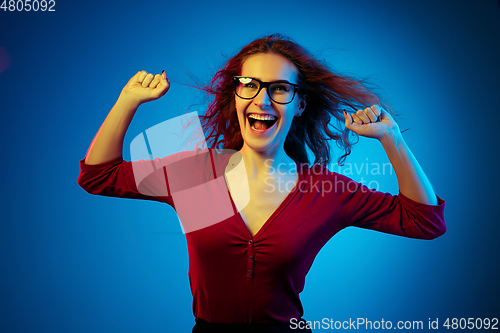 Image of Caucasian woman\'s portrait isolated on blue studio background in neon light