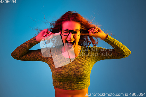 Image of Caucasian woman\'s portrait isolated on blue studio background in neon light