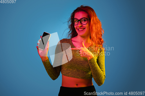 Image of Caucasian woman\'s portrait isolated on blue studio background in neon light