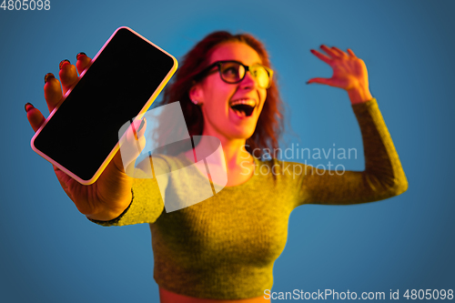 Image of Caucasian woman\'s portrait isolated on blue studio background in neon light