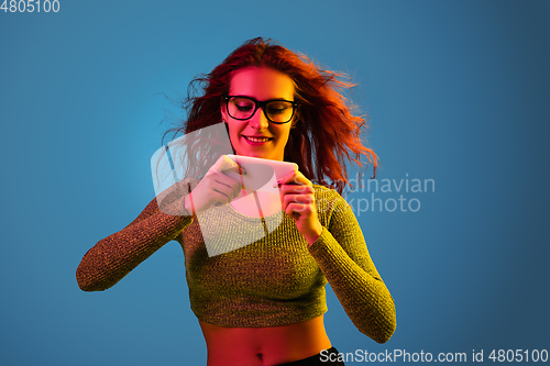 Image of Caucasian woman\'s portrait isolated on blue studio background in neon light