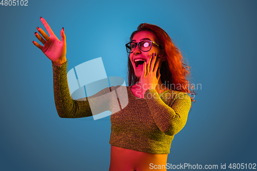 Image of Caucasian woman\'s portrait isolated on blue studio background in neon light