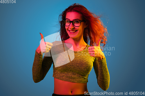 Image of Caucasian woman\'s portrait isolated on blue studio background in neon light