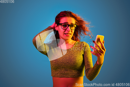 Image of Caucasian woman\'s portrait isolated on blue studio background in neon light