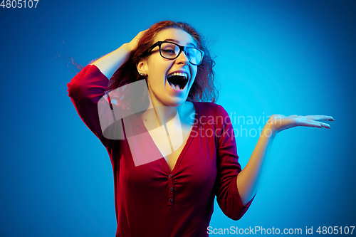 Image of Caucasian woman\'s portrait isolated on blue studio background in neon light