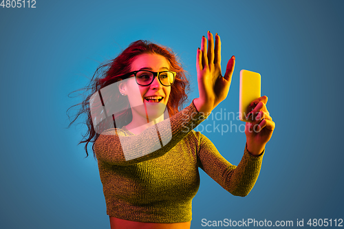 Image of Caucasian woman\'s portrait isolated on blue studio background in neon light