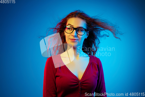 Image of Caucasian woman\'s portrait isolated on blue studio background in neon light
