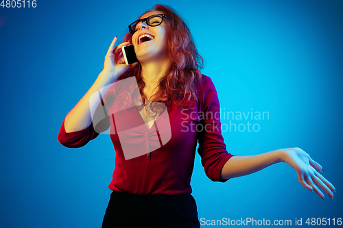 Image of Caucasian woman\'s portrait isolated on blue studio background in neon light