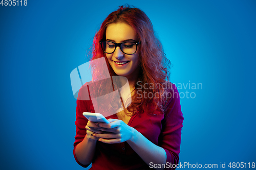 Image of Caucasian woman\'s portrait isolated on blue studio background in neon light
