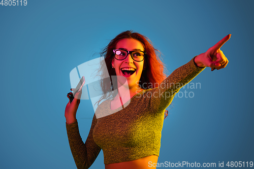 Image of Caucasian woman\'s portrait isolated on blue studio background in neon light