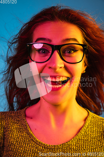 Image of Caucasian woman\'s portrait isolated on blue studio background in neon light