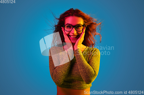 Image of Caucasian woman\'s portrait isolated on blue studio background in neon light