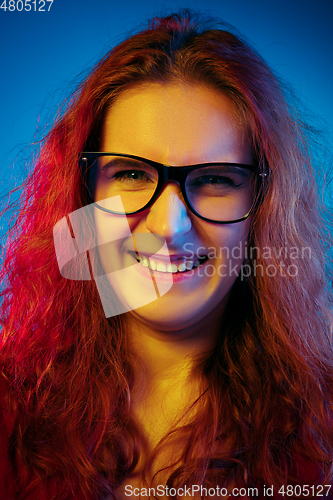 Image of Caucasian woman\'s portrait isolated on blue studio background in neon light