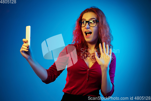 Image of Caucasian woman\'s portrait isolated on blue studio background in neon light