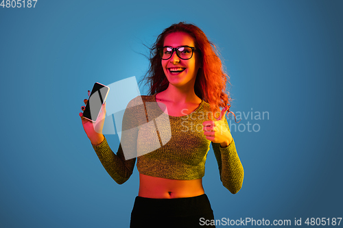 Image of Caucasian woman\'s portrait isolated on blue studio background in neon light