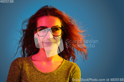 Image of Caucasian woman\'s portrait isolated on blue studio background in neon light