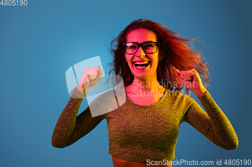Image of Caucasian woman\'s portrait isolated on blue studio background in neon light