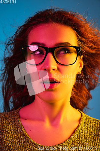 Image of Caucasian woman\'s portrait isolated on blue studio background in neon light